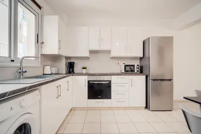 a kitchen with white cabinets and a stainless steel refrigerator at Apartment Helena in Ayia Napa
