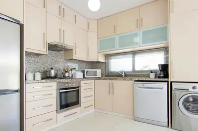a kitchen with white cabinets and a dishwasher at Villa Solebianco Protaras in Protaras