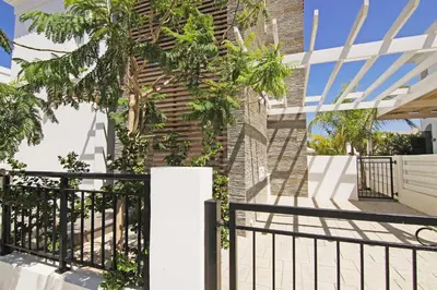 a black fence next to a building with a palm tree at Villa Solebianco Protaras in Protaras