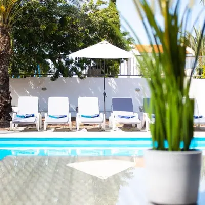 a group of chairs and an umbrella next to a pool at Villa Artemis in Larnaka