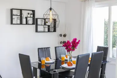 a dining room with a table with chairs and a vase of flowers at Protaras Fig Tree Bay Sea View Villa , Jacuzzi Available April to October in Protaras
