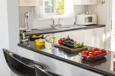 a kitchen with a counter with tomatoes and a glass of wine at Protaras Fig Tree Bay Sea View Villa , Jacuzzi Available April to October in Protaras