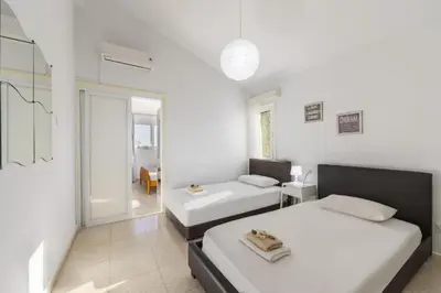 a white room with two beds and a table at Protaras Fig Tree Bay Sea View Villa , Jacuzzi Available April to October in Protaras