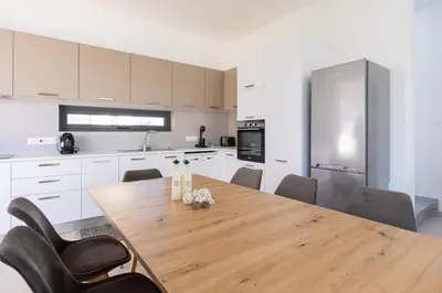 a large kitchen with a wooden table and chairs at Nelia Panorama Villa in Protaras