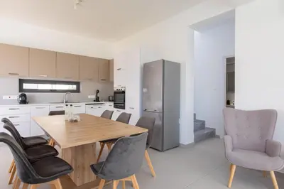 a kitchen and dining room with a wooden table and chairs at Nelia Panorama Villa in Protaras