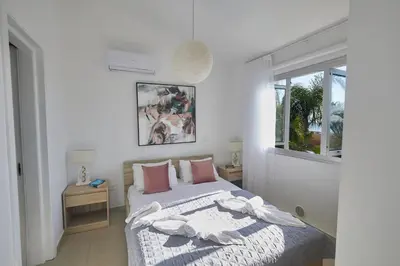 a white bedroom with a bed and a window at Sunrise Villa 9 in Ayia Napa