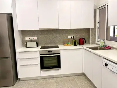 a white kitchen with white cabinets and a sink at Stasinou 52 in Limassol