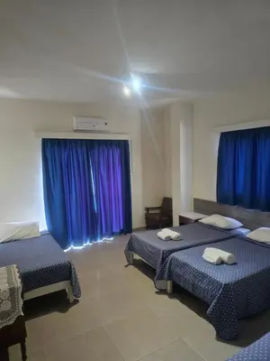 a room with two beds and blue curtains at Eleni Apartments in Ayia Napa