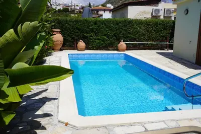 a blue swimming pool with vases next to a house at Villa Hanna mit Meerblick in Pissouri