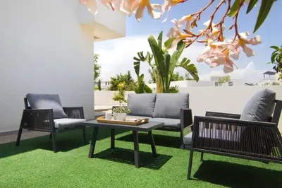 a patio with chairs and a table and grass at Villa Selena in Protaras