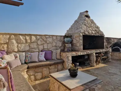 a stone wall with a couch and a stone fireplace at Oikos Selinolithos in Alaminos