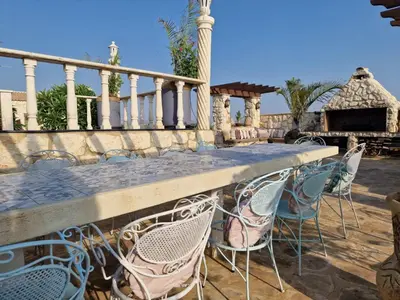 a patio with chairs and a table and a fireplace at Oikos Selinolithos in Alaminos