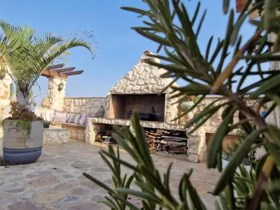 a stone fireplace in a yard with a palm tree at Oikos Selinolithos in Alaminos