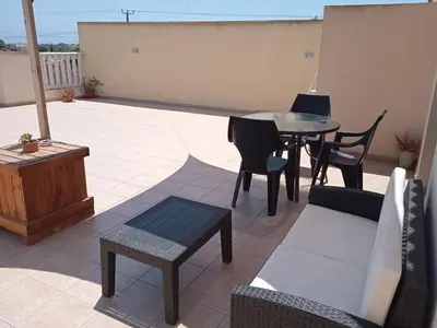 a patio with a table and chairs on a roof at Xylophagou Rest and Relax 2 Ayia Napa Larnaca 1 bedroom apartment in Xylophaghou