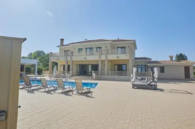 a large house with chairs and a swimming pool at Protaras Holiday Villa Pa7 Private 7 Bedroom villa in Protaras