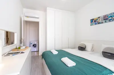 a white room with a bed and a washing machine at Lana 1-Bedroom Apt in Larnaca in Larnaka