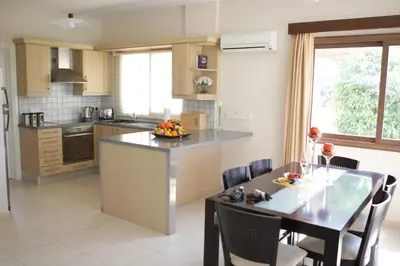 a kitchen with a table and a dining room at A three-bedroom villa with a private pool and landscaped garden Wi-Fi in Pissouri