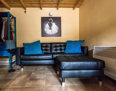 a living room with a black leather couch and blue pillows at Guesthouse Gonia in Pera Orinis