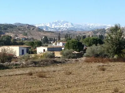a house in a field with mountains in the background at Guesthouse Gonia in Pera Orinis