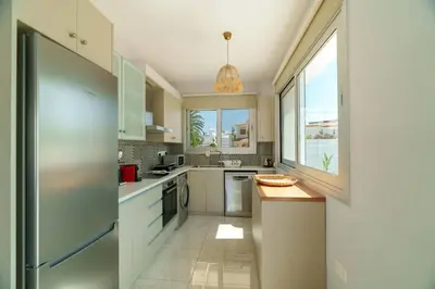 a kitchen with white cabinets and a large window at Geo Panoramic Villa Konnos - Pool, Game Room, Gym in Protaras