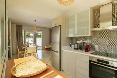 a kitchen with white cabinets and a dining room at Geo Panoramic Villa Konnos - Pool, Game Room, Gym in Protaras