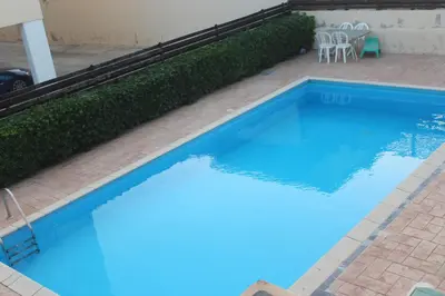a large blue swimming pool with a table and chairs at Marina Court Holiday Flat in Larnaka