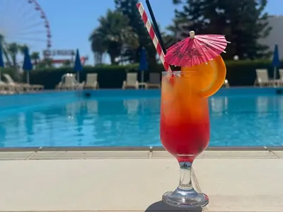 a drink with an orange slice and a pink umbrella at Napa Jay Hotel in Ayia Napa
