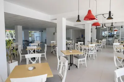 a restaurant with white tables and chairs and red lamps at Napa Jay Hotel in Ayia Napa