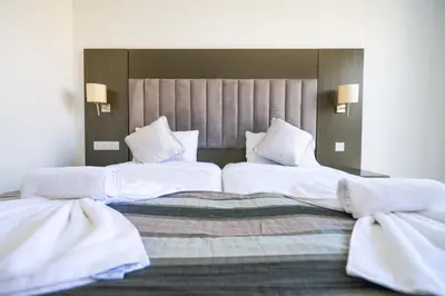 two beds in a hotel room with white sheets and pillows at Napa Jay Hotel in Ayia Napa