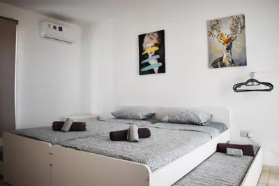two beds in a white room with paintings on the wall at Sunny Rooftop in Ayia Napa 91Sqm Terrace Delight! in Ayia Napa