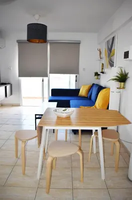 a dining room table with chairs and a blue couch at Sunny Rooftop in Ayia Napa 91Sqm Terrace Delight! in Ayia Napa