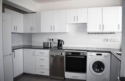 a kitchen with white cabinets and a washing machine at Sunny Rooftop in Ayia Napa 91Sqm Terrace Delight! in Ayia Napa