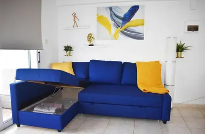 a blue couch in a living room with a table at Sunny Rooftop in Ayia Napa 91Sqm Terrace Delight! in Ayia Napa