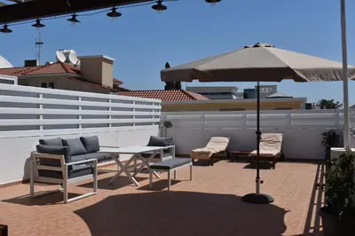 a patio with a table and chairs and an umbrella at Sunny Rooftop in Ayia Napa 91Sqm Terrace Delight! in Ayia Napa