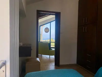 a bedroom with a door open to a room with a chair at Mediterranean View Villa in Protaras