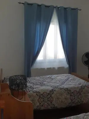 a bedroom with a bed and a window with blue curtains at Indie7house in Pano Lefkara