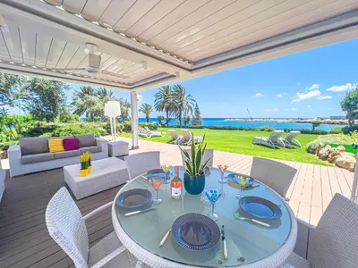a patio with a table and chairs on a deck at Erato Seafront Luxury Villa in Protaras