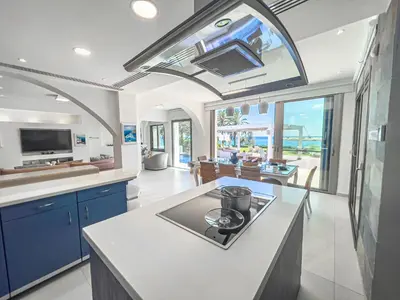 a kitchen with blue cabinets and a large window at Erato Seafront Luxury Villa in Protaras