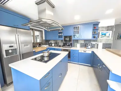 a blue kitchen with white counters and blue cabinets at Erato Seafront Luxury Villa in Protaras