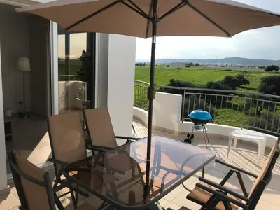 a glass table and chairs with an umbrella on a balcony at Oceania Bay Penthouse in Pyla