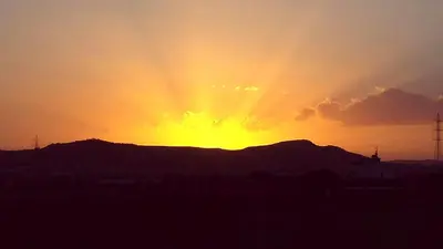 a sunset over a hill with the sun setting behind a mountain at Oceania Bay Penthouse in Pyla