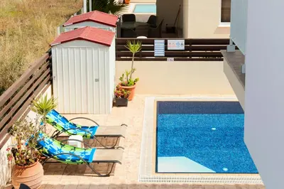 a patio with a swimming pool and two lawn chairs and a swimming pool at VILLA ICARUS IN THE HEART OF PROTARAS in Protaras