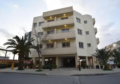a white building with a palm tree in front of it at Elysso Apartments in Larnaka