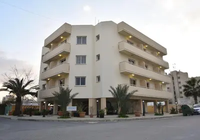 a large white building with trees in front of it at Elysso Apartments in Larnaka