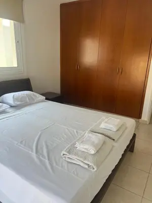 a bedroom with a bed with white sheets and a wooden cabinet at Chara Cynthiana Villa in Paralimni
