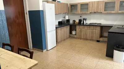 a kitchen with a white refrigerator and wooden cabinets at Unique City Hostel 100 meters from Beach in Larnaka