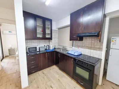 a kitchen with wooden cabinets and a black counter top at Home Sweet Home Apartment in Larnaka