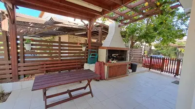 a wooden pergola with a bench and an outdoor oven at Comfortable 2BR Seaside House & Free Parking in Larnaka