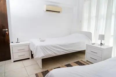 a white bedroom with two beds and a window at Private room in shared flat in Nicosia