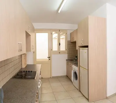 a kitchen with wooden cabinets and a washer and dryer at Private room in shared flat in Nicosia